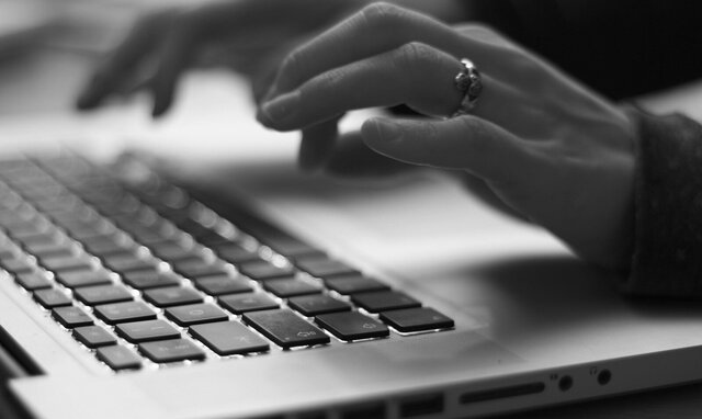 Hands typing on a laptop keyboard